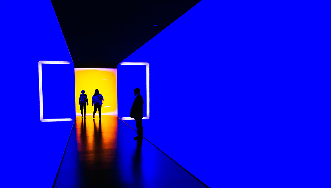 Two light up blue walls surrounding people walking towards a yellow wall. FundApps guide Hedge Fund clients with compliance monitoring and reporting. 