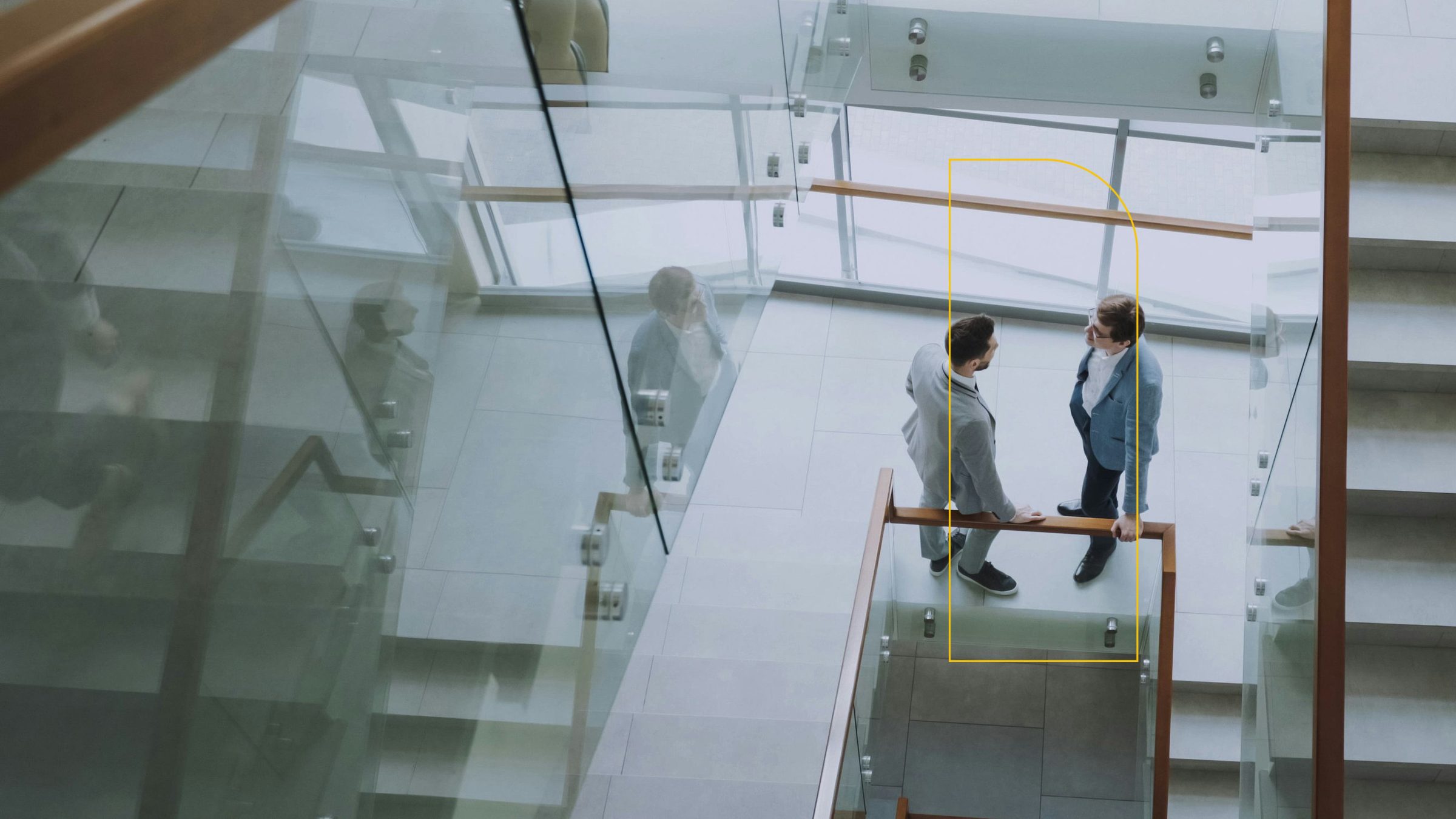 Two colleagues talking on a glass staircase